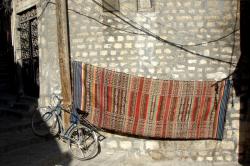 A bicycle propped up next to a carpet