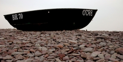 A boat on a rocky, foggy beach.