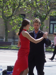 A couple dancing tango in front of local cafes.