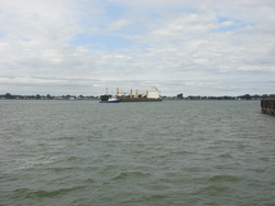 A couple tugs help turn a container ship around